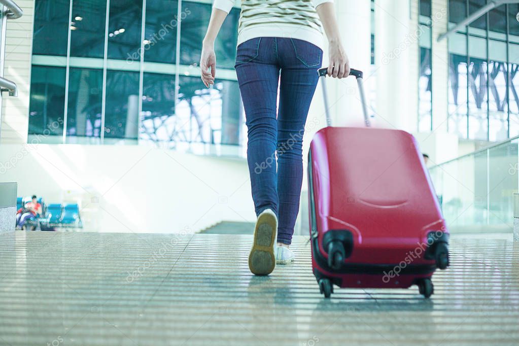 leg view of a woman in hurry with cabin size bag in airport