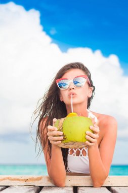 uzun saçlı kadın bikini ve taze hindistan cevizi tropik sahilde rahatlatıcı kokteyl ile güneş gözlüğü