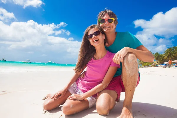 Closeup of happy young caucasian couple in bright clothes laughing at beach — Stock Photo, Image