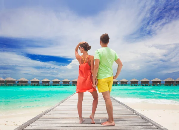 Glada unga par promenader på träbro vid stranden. Maldiverna — Stockfoto
