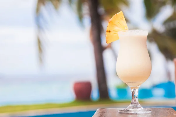 Glas leckerer Pina-Colada-Cocktail am Meer lizenzfreie Stockbilder