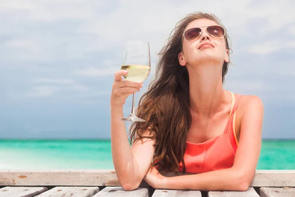 Swimsuitrelaxing 的美女在海边的木桥上喝着一杯白葡萄酒。马尔代夫 免版税图库图片