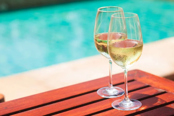 Elegantní flétna sklenice šumivého bílého vína nebo šampaňského vedle bazénu Royalty Free Stock Obrázky