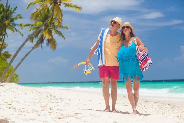 Šťastný mladý pár s plážové doplňky baví u pláže — Stock fotografie