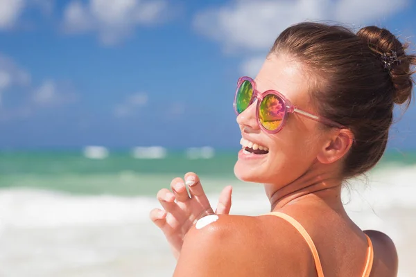Primer plano de la mujer joven en gafas de sol poniendo crema solar en el hombro —  Fotos de Stock