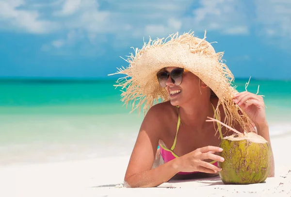 Mujer joven feliz sonriendo en sombrero de paja con cóctel de coco en la playa — Foto de Stock