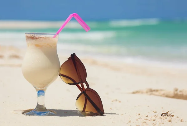 Foto de pina colada e óculos de sol na praia tropical — Fotografia de Stock