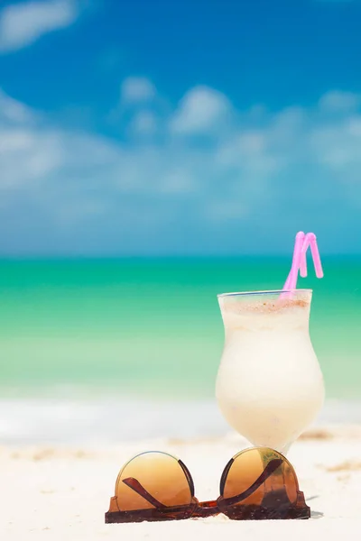 Zdjęcie pina colady i okularów słonecznych na tropikalnej plaży — Zdjęcie stockowe