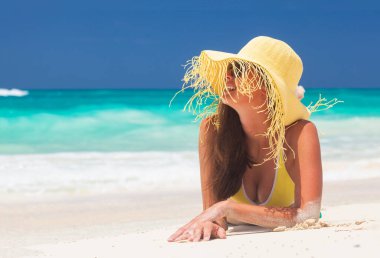 Genç bayan tropikal sahilde güneşli bir günün tadını çıkarıyor.