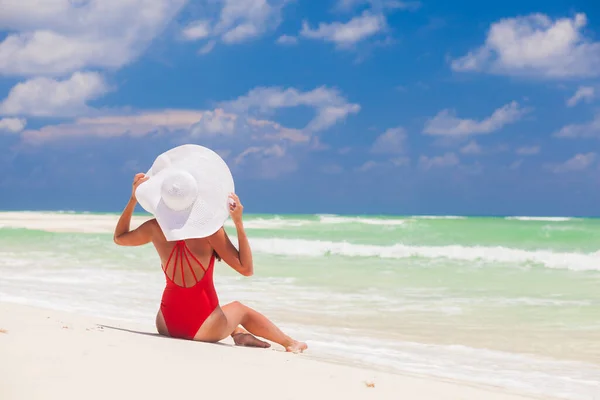 Jonge vrouw in bikini en witte strohoed ontspannen op wit kariboenstrand — Stockfoto