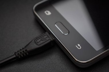 siyah arka plan üzerine siyah şarj cihazı ile siyah smartphone