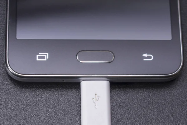 Smartphone preto no fundo preto com cabo branco — Fotografia de Stock