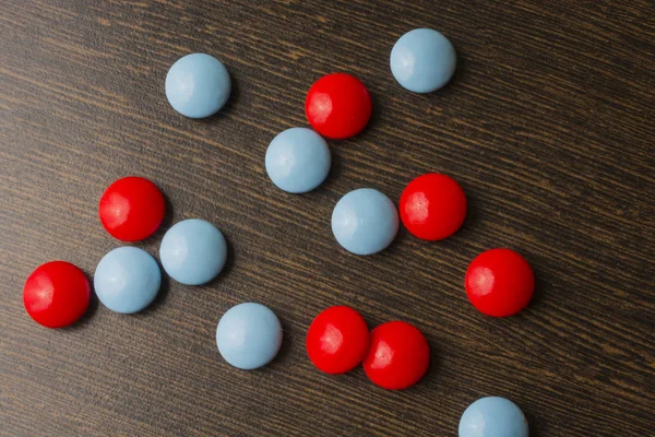 Red and blue pills on a wooden background.