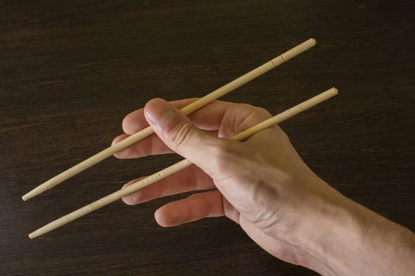 Stäbchen in der rechten Hand auf dem Hintergrund von Holz — Stockfoto