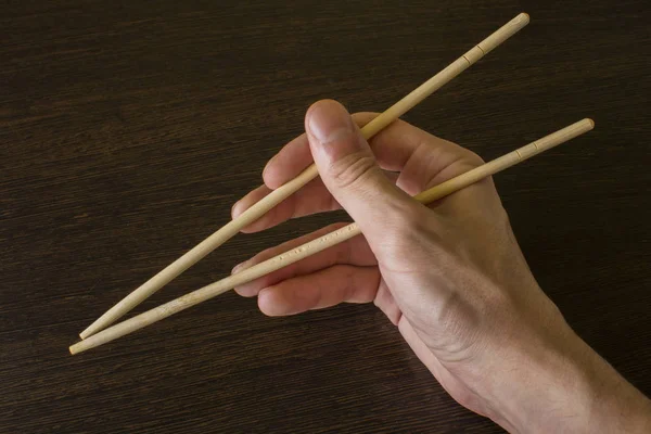 Palillos en la mano derecha sobre el fondo de madera —  Fotos de Stock