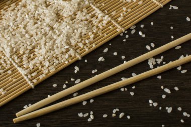 hangi dağınık pirinç yalan chopsticks yanındaki bir suşi mat