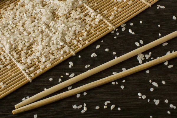 hangi dağınık pirinç yalan chopsticks yanındaki bir suşi mat