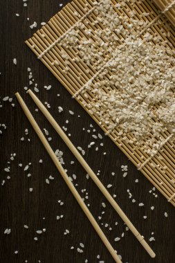 hangi dağınık pirinç yalan chopsticks yanındaki bir suşi mat