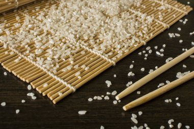 hangi dağınık pirinç yalan chopsticks yanındaki bir suşi mat