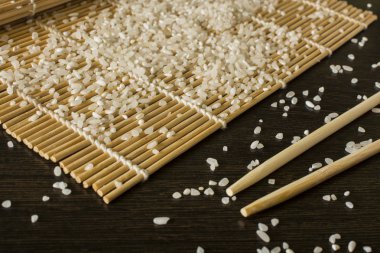 hangi dağınık pirinç yalan chopsticks yanındaki bir suşi mat
