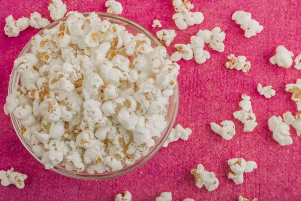 Popcorn in einem Glasteller, auf rosa Hintergrund — Stockfoto