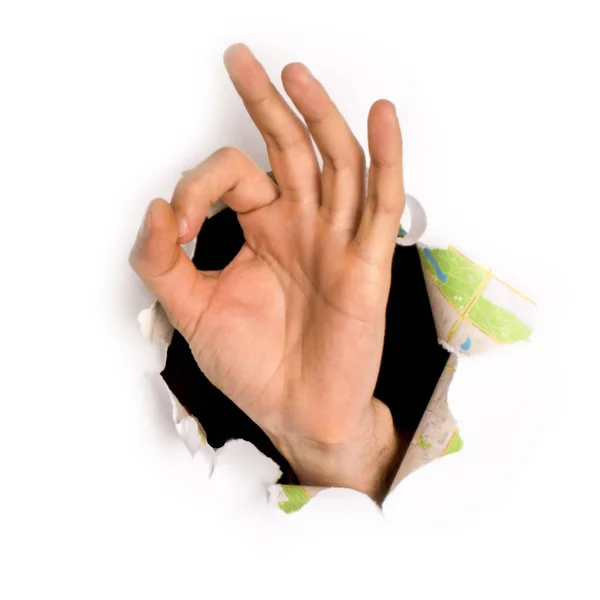 Primer plano de la mano femenina que sale de un agujero en un papel, signo bien, aislado en blanco — Foto de Stock