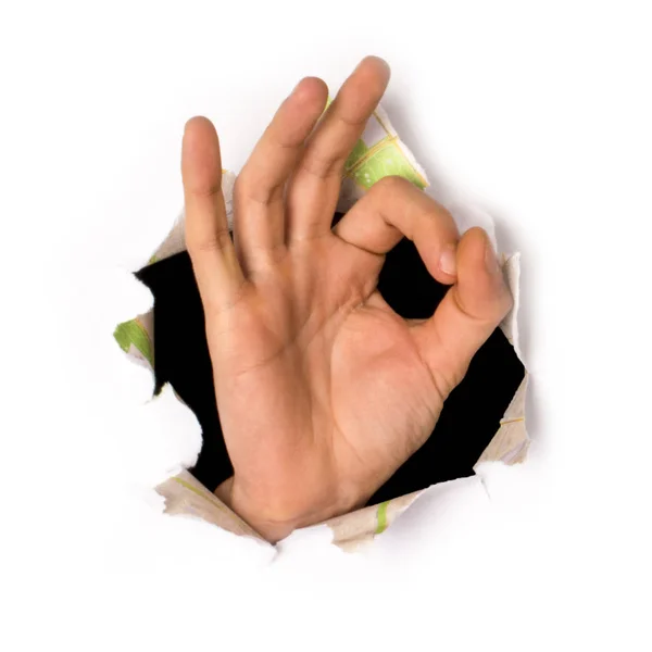 Close-up da mão feminina saindo de um buraco em um papel, ok sinal, isolado em branco — Fotografia de Stock
