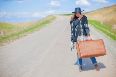 Mavi Jeans, panço, bir kız bir siyah deri şapka elleri bir eski kahverengi çantada ile yola çıktı..