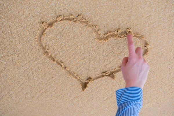 Das Herz wird mit dem Finger auf den Sand in der Nähe des Ozeans gezogen. — Stockfoto