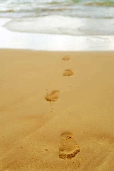 Stopy bosých nohou člověka na písku z oceánu na th — Stock fotografie
