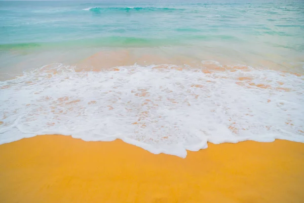 Blue waves of the ocean and yellow sand of the beach.