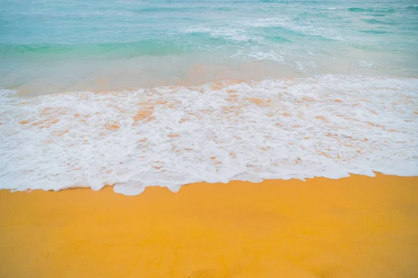 Blue waves of the ocean and yellow sand of the beach.