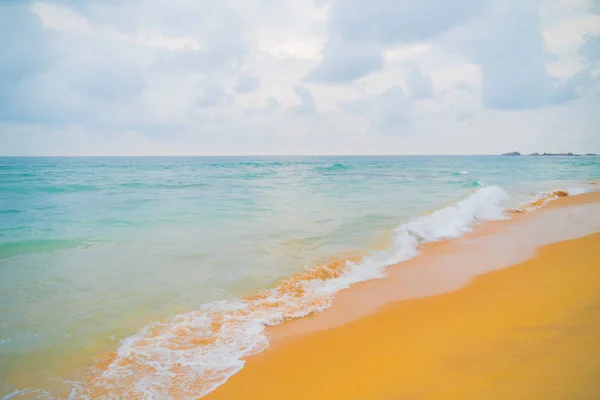 Blue waves of the ocean and yellow sand of the beach.