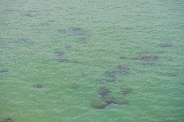 Surface of water in shallow water. Stones under the water.