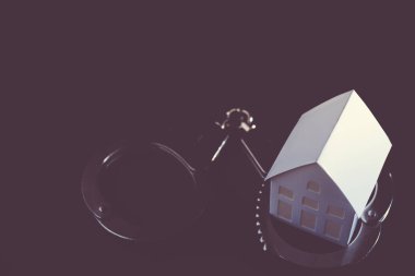 Siyah üzerine kelepçeli beyaz minyatür ev modelinin yakın plan görüntüsü.