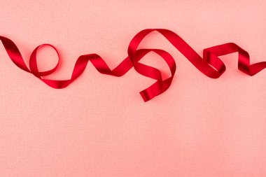 Pembe arka planda kırmızı dalgalı kurdele. Tatil dekorasyonu. Valentin.
