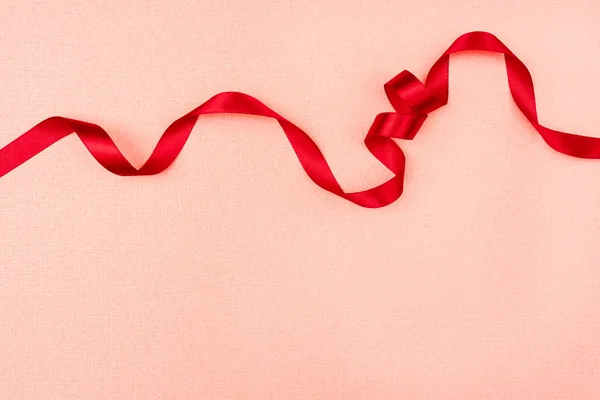 Red wavy ribbon on pink background. Holiday decoration. Valentin — Stock Photo, Image