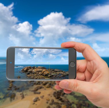 Kıyıya yakın okyanusta büyük kayalar. Fotoğraf akıllı telefon. Akıllı telefon içeri.