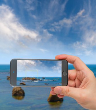 Kıyıya yakın okyanusta büyük kayalar. Fotoğraf akıllı telefon. Akıllı telefon içeri.