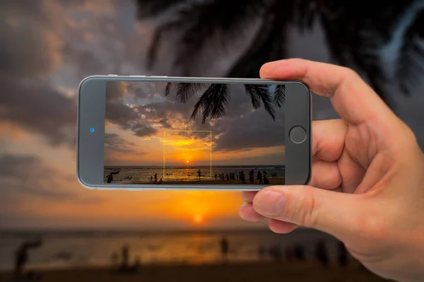 Puesta de sol en el océano. Los turistas son fotografiados en la costa. Smartph. — Foto de Stock