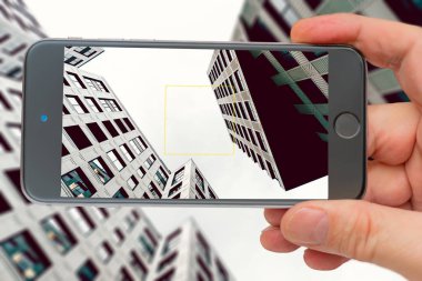 Modern şehrin yüksek binaları. Fotoğraf akıllı telefon. Akıllı telefon elindeydi. Ekrandaki binalar.