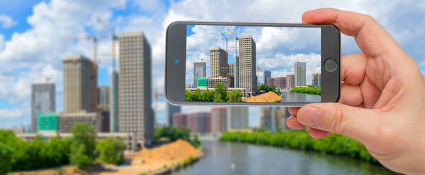 Строительство высотных жилых зданий в современном городе. Фото смартфон. Смартфон в руке. Здания на экране
.