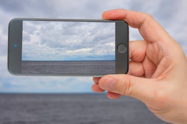 Akıllı telefon ekranındaki su manzarası. Gri gökyüzü bulutlu