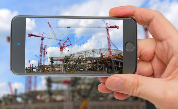 Construction on smartphone screen. Construction cranes on backgr