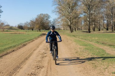 Pantolon ve yün ceketli bir bisikletçi. Havalandırma çatallı, modern bir karbon motorlu. Tepedeki adam bisiklete biniyor..
