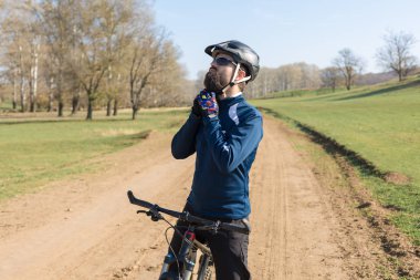 Pantolon ve yün ceketli bir bisikletçi. Havalandırma çatallı, modern bir karbon motorlu. Tepedeki adam bisiklete biniyor..