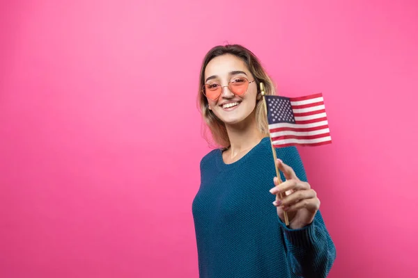 幸せな若いです女性ハート型の眼鏡保持アメリカの旗に対してAスタジオピンクの背景 — ストック写真
