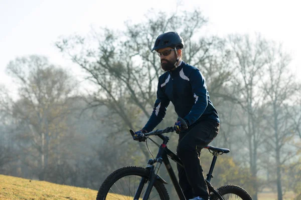 Cyclist in pants and fleece jacket on a modern carbon hardtail bike with an air suspension fork. The guy on the top of the hill rides a bike.