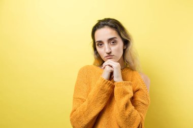 Turuncu süveter giyen güzel bir kızın portresi, düşünceli bir ifadeyle, daha ileri bir eylem planı düşünüyor..