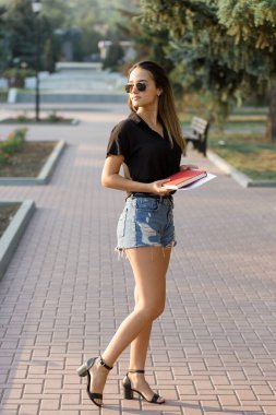 Genç bir kız parkta bir bankta oturur ve notlar yapar. Serbest stilde giyinmiş. Müşterilerle telefonda konuşan iş kadını.